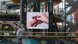 An image of a digital screen in a shopping centre showing the artwork ‘European Pa55port’ (2023), by David Blackmore.