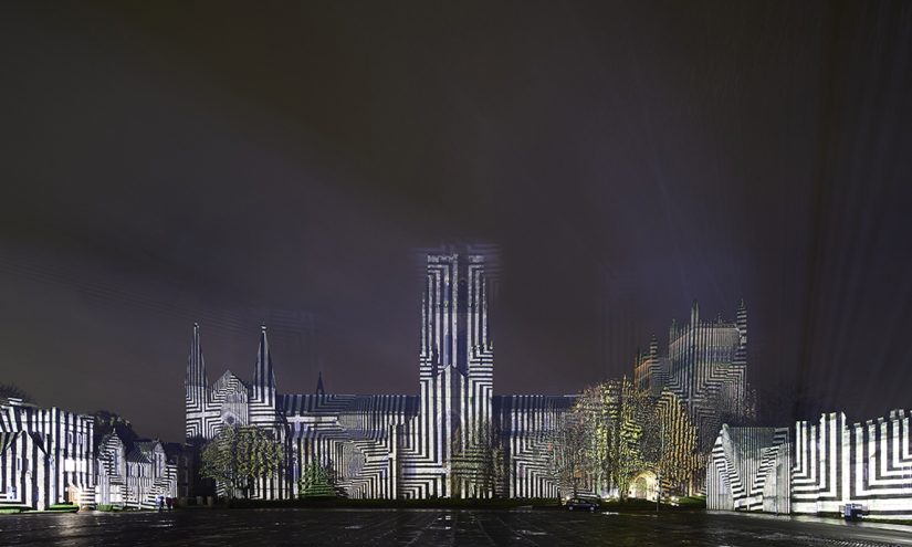 Durham Cathedral lit up at night with monochrome geometric shapes.