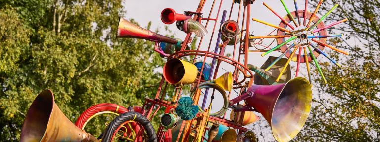 A close up of the tip of The Babylon Gamelan by Rag & Bone, created by artist Dave Young, 2024. Horns, gloves, bike wheels and all sorts of reclaimed and repainted junk are attached to the 4 metre tall structure. Photo by Andrew Moore