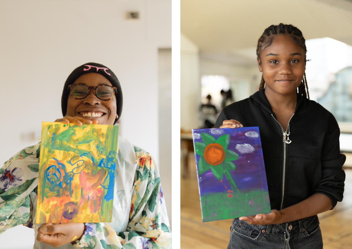 Two young people look into the camera smiling as they hold their artworks proudly.