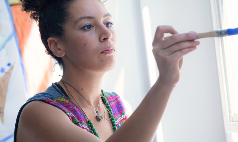 Tasnim Mahdy holds a paintbrush covered in blue paint