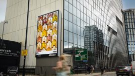 A busy city scene showing the artwork from The Gallery Season 4 on billboards. The artwork on display: A grid of tessellating sculptural tiles shaped like different sets of breasts.