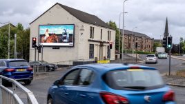 A busy city scene showing the artwork from The Gallery Season 4 on billboards. The artwork on display: A person with red hair sits confidently atop a horse under the text 